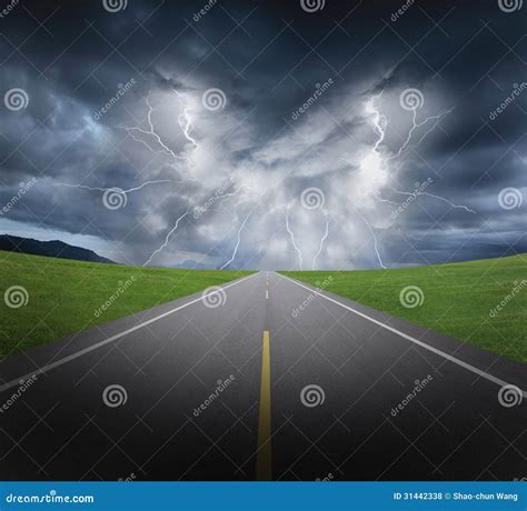 Rainstorm Clouds and Lightning with Asphalt Road and Grass Stock Photo