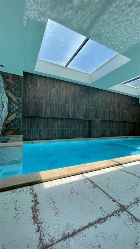 An Indoor Swimming Pool With Skylights And Tiled Flooring Is Pictured