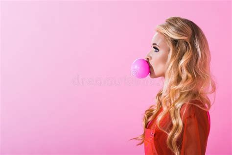 Side View Of Beautiful Girl Blowing Bubble Gum On Pink Doll Concept