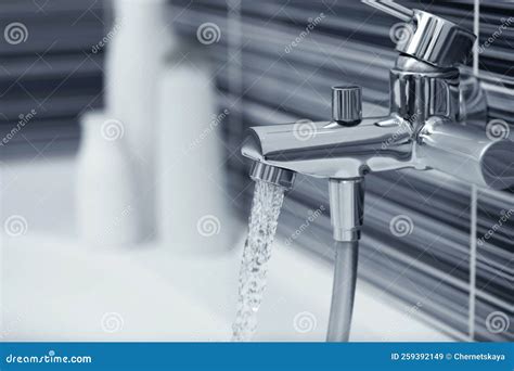 Water Flowing From Bath Tap Installed On Black And White Wall Stock