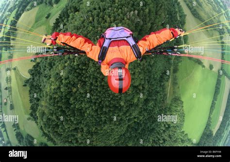 Paraglider flying in 500 ft above ground relaxed in upwind over woody ...