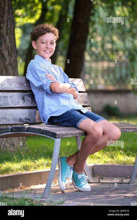 Young Happy Child Boy Relaxing Sitting On Bench In Summer Park