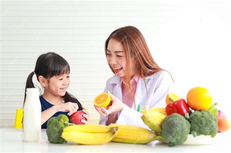 Nutrición Para Niños En Edad Escolar Una Bella Nutricionista O Doctora Le Explica A Una Niña Los