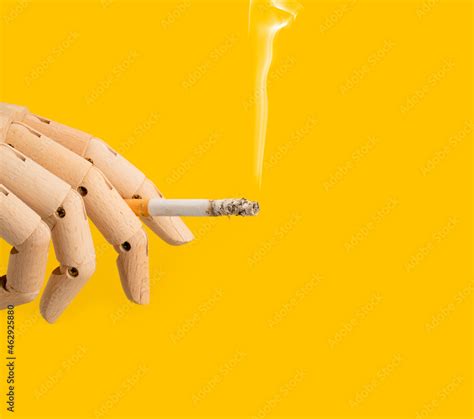 Hand holding a smoking Cigarette on a yellow Background. Isolated hand ...