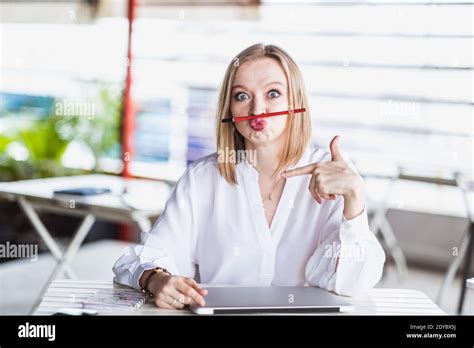 Young European Funny Woman Holding A Pen Between Nose And Lips As