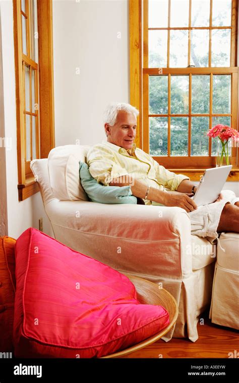 Mature Man Holding A Laptop And Sitting On A Couch Stock Photo Alamy