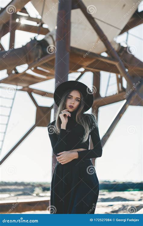 A Long Haired Blonde Woman Dressed All In Black Wearing A Black