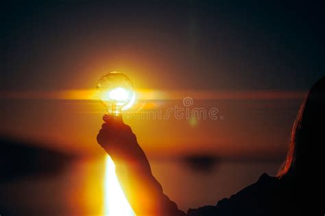 Persona Portando Una Bombilla Llena De Energía Solar Al Atardecer Stock