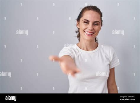 Beautiful Brunette Woman Standing Over Isolated Background Smiling Friendly Offering Handshake