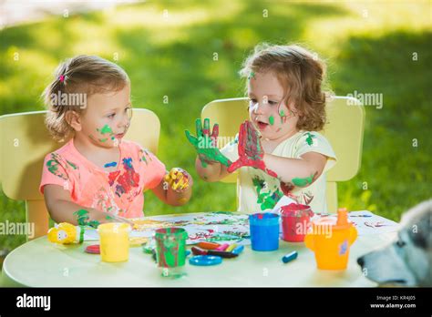 Two Year Old Girls Painting With Poster Paintings Together Against