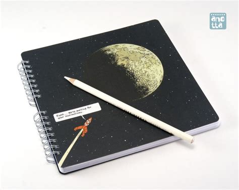 An Open Notebook With A Pencil On Top Of It And The Moon In The Background