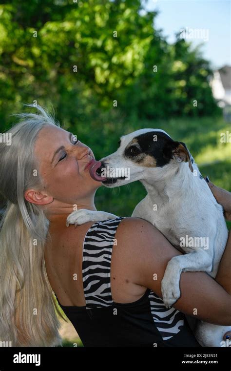 Im Garten Steht Jungen Blonde Huebsche Frau Wird Vom Hund Im Arm Mit Ausgestreckter Zunge
