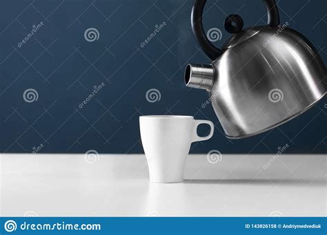 White Mug With Kettle On A White Table Kettle Pouring Boiling Water