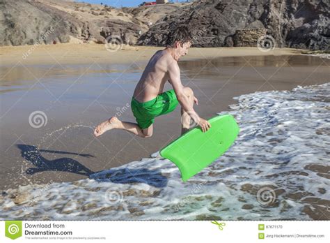 El Muchacho Se Divierte El Practicar Surf En Las Ondas Foto De Archivo