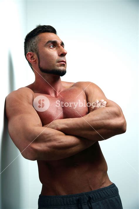 Portrait Of A Thoughtful Muscular Man With Arms Folded Leaning On The