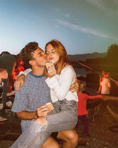 A Man And Woman Kissing Each Other In Front Of An Outdoor Fire Pit At Night