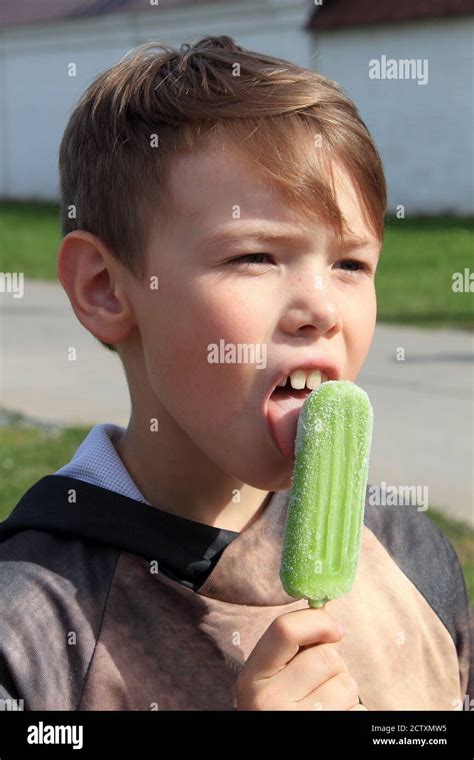 Teenager boy with blonde hair licking ice cream outdoor on sunny day ...