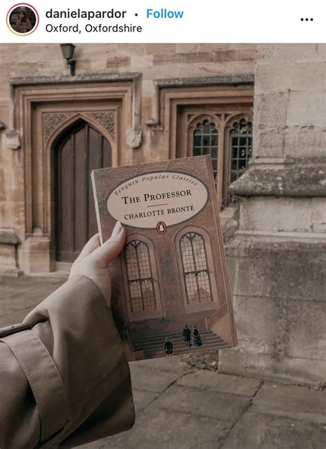 A Person Holding Up A Book In Front Of A Building With An Arched