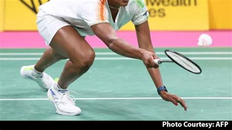 A Female Tennis Player Is Bending Down To Hit The Ball With Her Racquet