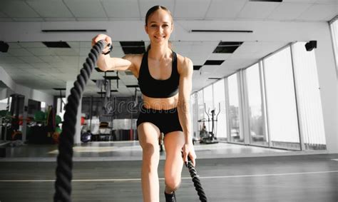 Athletic Female In A Gym Exercises With Battle Ropes During Her Fitness