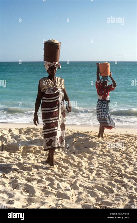 Local Women Carrying Buckets Of Sand On Their Heads On The Beach At