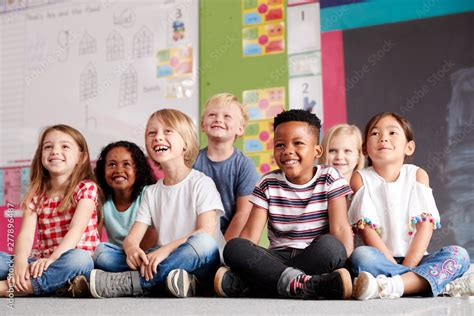 Group Of Elementary School Pupils Sitting On Floor In Classroom Stock Photo | Adobe Stock