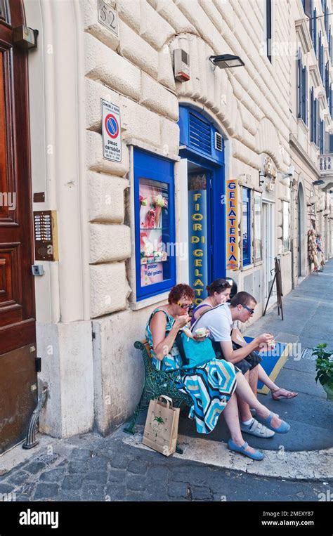 Mother With Son And Daughter Eating Ice Cream Outside Gelato Shop In