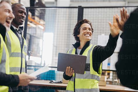 Happy Warehouse Workers High Fiving Each Other During A Staff Meeting