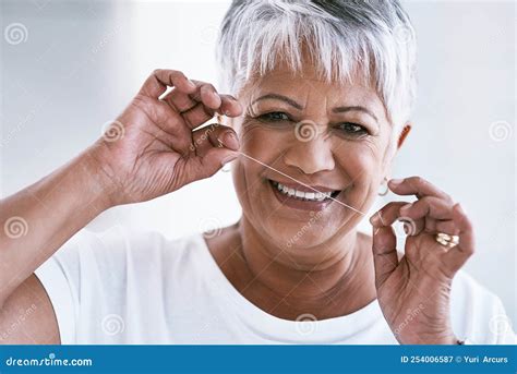 Making My Smile Look Even Better Portrait Of A Cheerful Mature Woman Flossing Her Teeth While