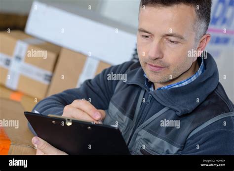 Happy Delivery Man With Clipboard In The Warehouse Stock Photo Alamy