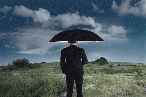 Premium Photo | Businessman with an umbrella standing under the rain