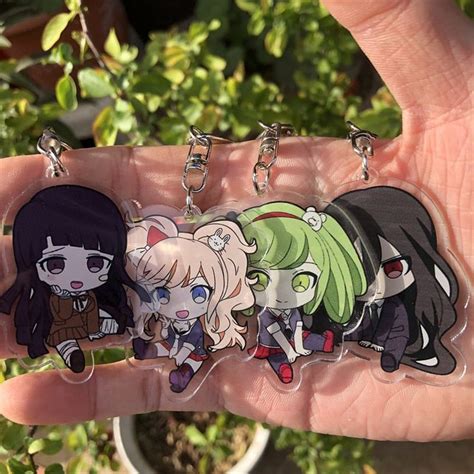 Three Anime Keychains In The Palm Of Someone S Hand With Plants In The