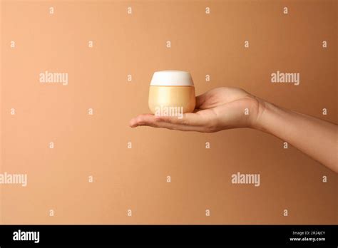 Woman Holding Jar Of Face Cream On Beige Background Closeup Space For