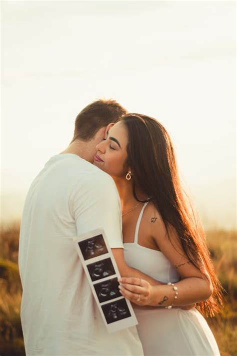 Happy Couple Hugging While Woman Holding Ultrasound Pictures of Baby · Free Stock Photo