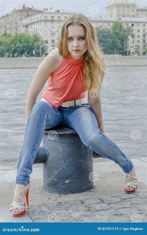 Jeune Belle Fille Blonde Dans Une Pose Rouge De Chemisier Et De Jeans D été Flexible Image stock