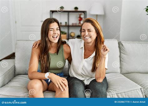 Mother And Daughter Together Sitting On The Sofa At Home Winking