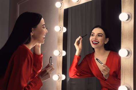 Premium Photo Beautiful Woman Applying Makeup Near Mirror In Room