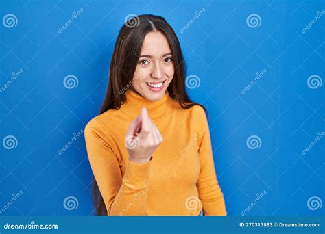 Young Brunette Woman Standing Over Blue Background Beckoning Come Here