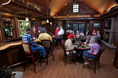 a group of people sitting at tables in a room with wood floors and ...