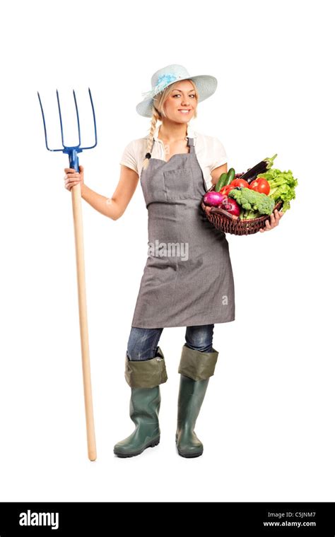 Full Length Portrait Of A Female Farmer Holding A Pitchfork And Basket