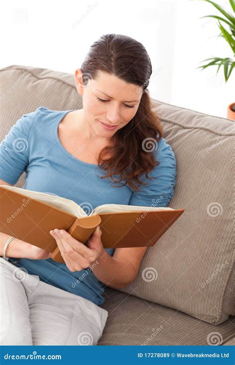 Attentive Woman Reading A Book Sitting On Her Sofa Stock Image Image