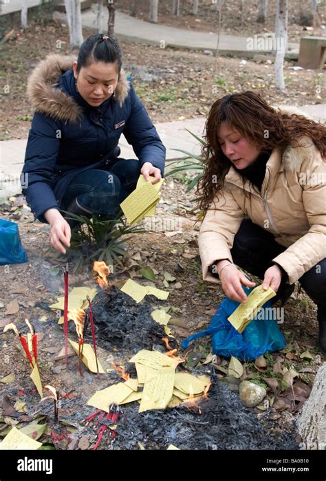 Two Women Burn Paper Money As Offerings To Appease The Spirits Of Their