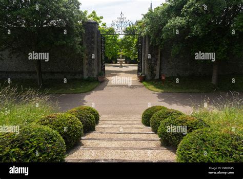 A Path Lined With Clipped Box Balls Outside Large Black Wrought Iron