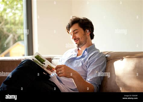 Man sitting on couch reading catalogue Stock Photo - Alamy