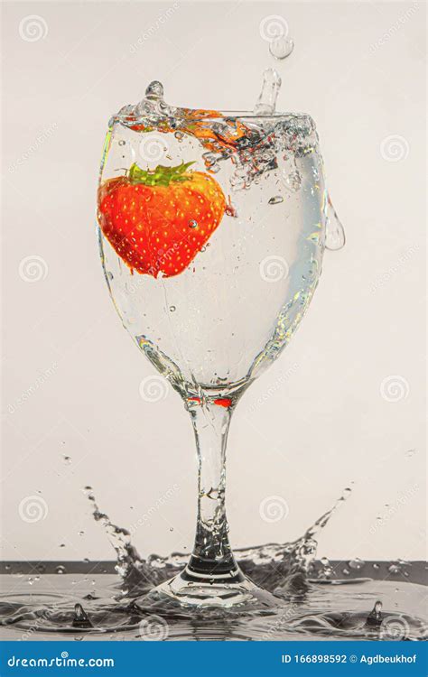 Fresh Strawberry Dropped Into Water With Splash On White Backgrounds