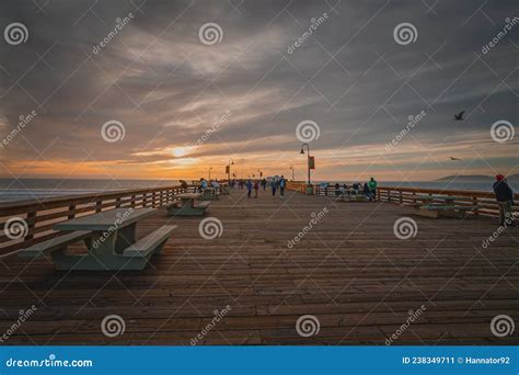 Pismo Beach Pier at Sunset with Walking People Enjoying Ocean View and Beautiful Cloudy Sky on ...