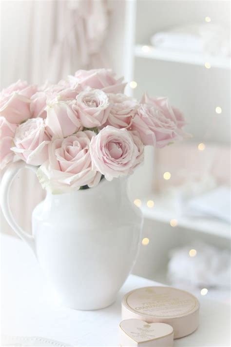 A White Vase Filled With Pink Roses On Top Of A Table