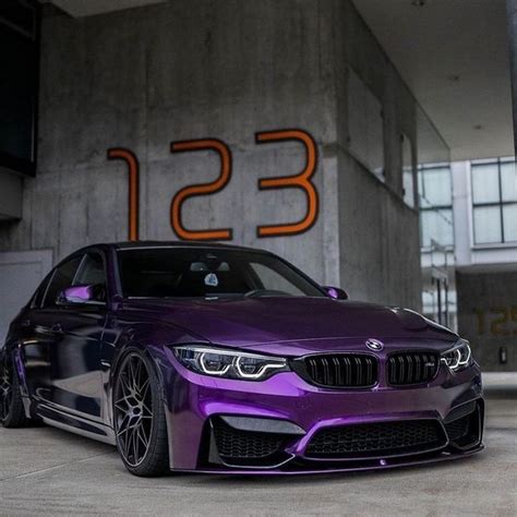 A Purple Bmw Car Parked In Front Of A Building With The Number On It