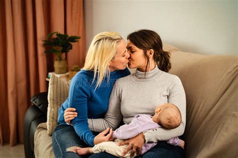 Happy Lesbian Couple Having Tender Moments With Their Small Baby At Home Stock Photo Image Of