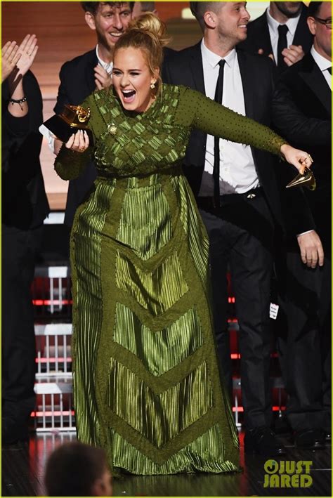 a woman in a long green dress holding an award while other people stand ...